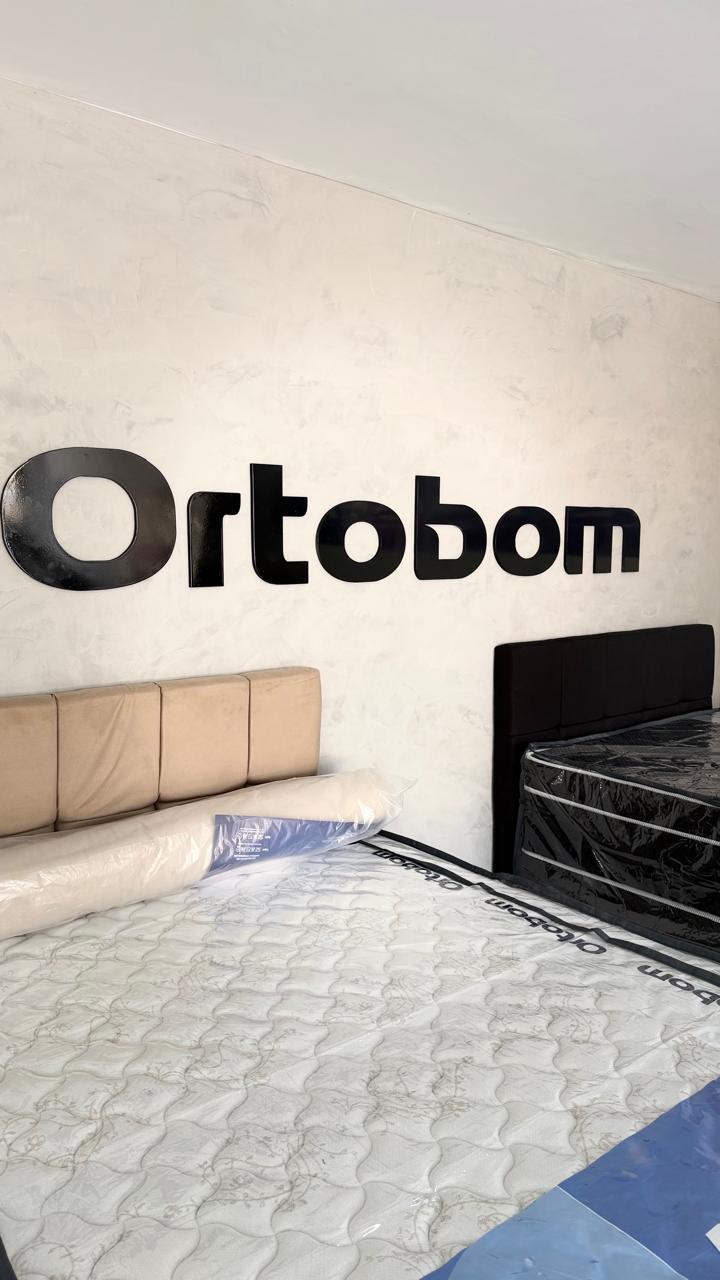 Parede com a marca Ortobom e colchões expostos no showroom